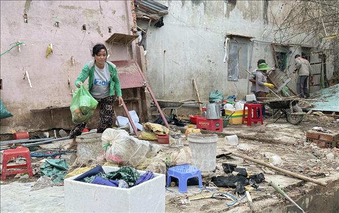Chị Đặng Thùy Trang (khu phố Phước Khánh, phường Tuy Hòa) được hàng xóm hỗ trợ dọn dẹp nhà bị sập do mưa lũ. Ảnh: Tường Quân - TTXVN