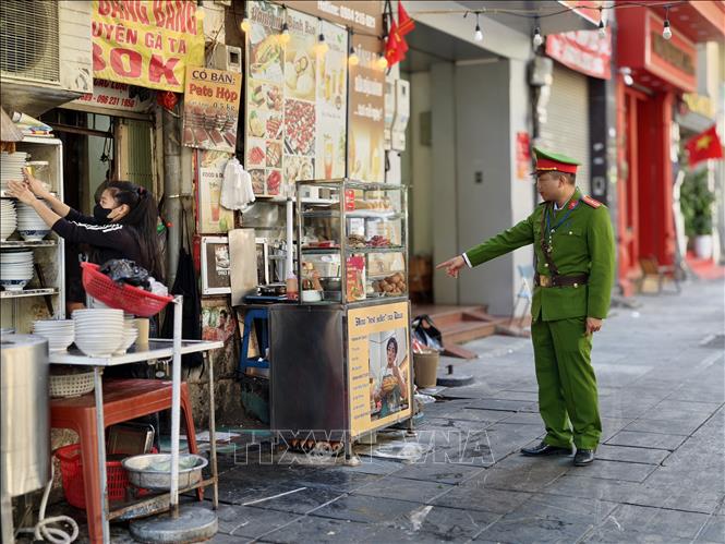Lực lượng chức năng đi vận động hộ kinh doanh không lấn chiếm vỉa hè tại phố Phan Chu Trinh, phường Cửa Nam. Ảnh: Quốc Lũy - TTXVN
