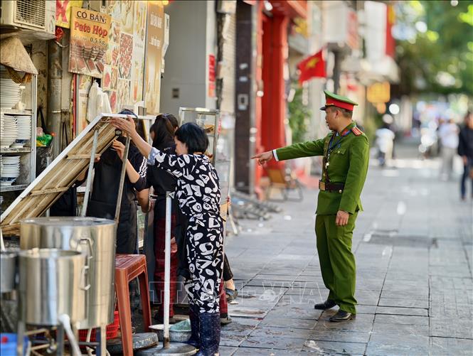 Lực lượng chức năng đi vận động hộ kinh doanh không lấn chiếm vỉa hè tại phố Phan Chu Trinh, phường Cửa Nam. Ảnh: Quốc Lũy - TTXVN