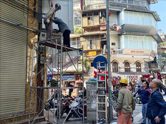 Lực lượng chức năng phường Hoàn Kiếm cùng những hộ dân tiến hành tháo dỡ mái hiên, thực hiện nghiêm túc các quy định về trật tự đô thị trên địa bàn. Ảnh: Quốc Lũy - TTXVN