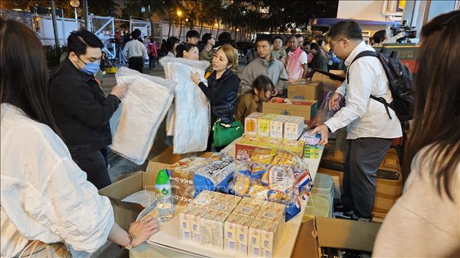 Phát nhu yếu phẩm cho người dân khu chung cư ở quận Tai Po, Hong Kong (Trung Quốc) sau vụ hỏa hoạn. Ảnh: THX/TTXVN