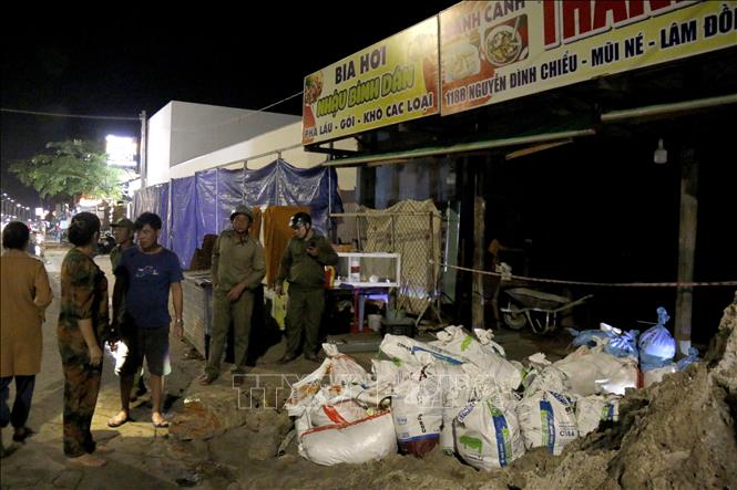 Lực lượng chức năng phường Mũi Né (Lâm Đồng) có mặt hỗ người dân đấp bao cát ngăn nước biển. Ảnh: Nguyễn Thanh - TTXVN