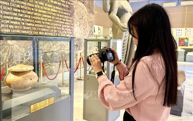 Khách du lịch thích thú tham quan bảo vật Quốc gia Mộ vò Gò Cây Trâm trưng bày tại Khu trưng bày Văn hóa Óc Eo. Ảnh: Thanh Sang - TTXVN