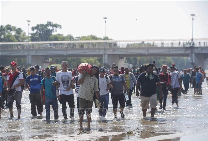 Người di cư Trung Mỹ vượt sông Suchiate từ Guatemala để tới Mexico, trong hành trình đến Mỹ. Ảnh: THX/TTXVN