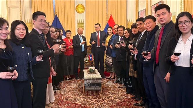 Cán bộ, nhân viên Đại sứ quán Việt Nam và Đại sứ quán Lào tại Pháp nâng cốc chúc mừng nhân kỷ niệm 50 năm Quốc khánh Lào (02/12/1975). Ảnh: Hữu Chiến - P/v TTXVN tại Pháp