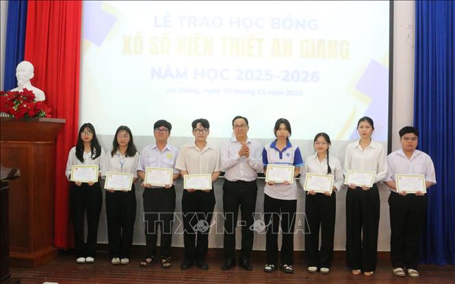 Ông Ngô Vũ Hải, Phó Giám đốc Công ty TNHH MTV Xổ số kiến thiết An Giang trao học bổng cho các em học sinh, sinh viên nghèo hiếu học. Ảnh: Công Mạo - TTXVN