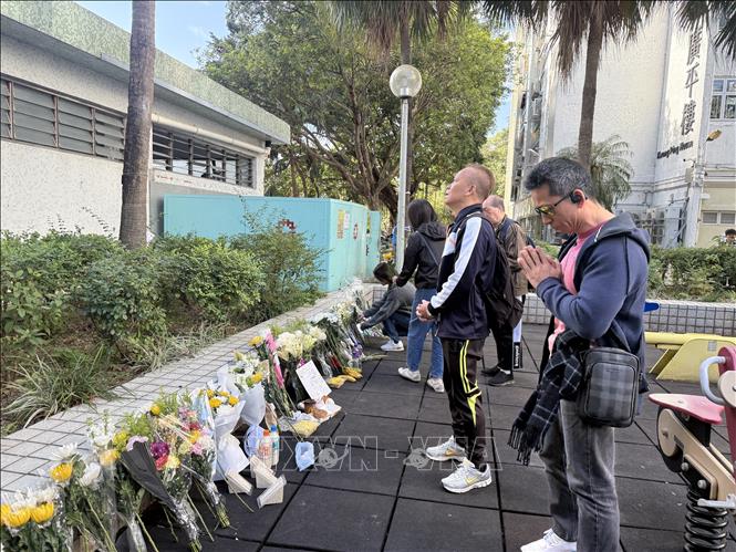 Người dân mang hoa đến gần nơi xảy ra hỏa hoạn để bày tỏ thương tiếc đối với các nạn nhân. Ảnh: Mạc Luyện PV TTXVN tại Hong Kong