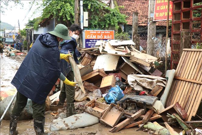 Lực lượng công an hỗ trợ nhân dân dọn vệ sinh môi trường ngay sau nước lũ rút.  Ảnh: Tuấn Anh - TTXVN