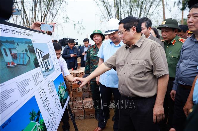 Thủ tướng Phạm Minh Chính thăm vùng ngập nước hoàn toàn tại thôn Phú Hữu, xã Hòa Thịnh và nghe báo cáo về phương án xây dựng nhà tránh lũ cho bà con, nhân dân vùng lũ. Ảnh: Dương Giang-TTXVN 
