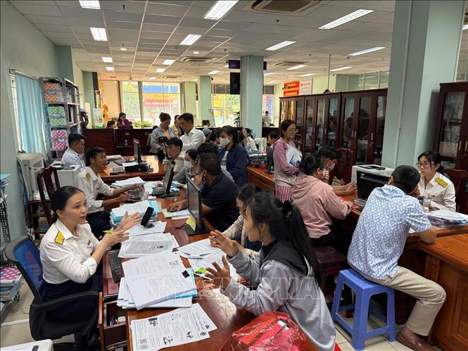 Cán bộ Thuế Cơ sở 12 (thuộc Thuế TP. Hồ Chí Minh) tập trung giải đáp các vướng mắc cho hộ kinh doanh trước thời điểm chuyển đổi mô hình quản lý thuế. Ảnh: Hứa Chung-TTXVN