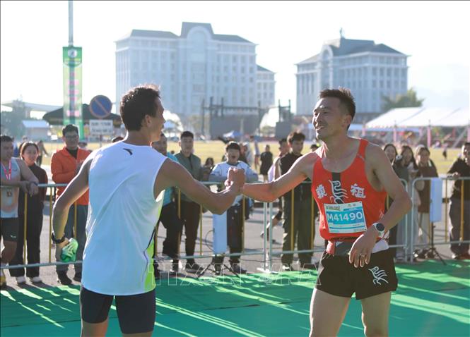 Vận động viên Trương Văn Quân về nhất nội dung 42km nam chúc mừng vận động viên của Trung Quốc về thứ 2 nội dung 42 km nam. Ảnh: Quý Trung – TTXVN