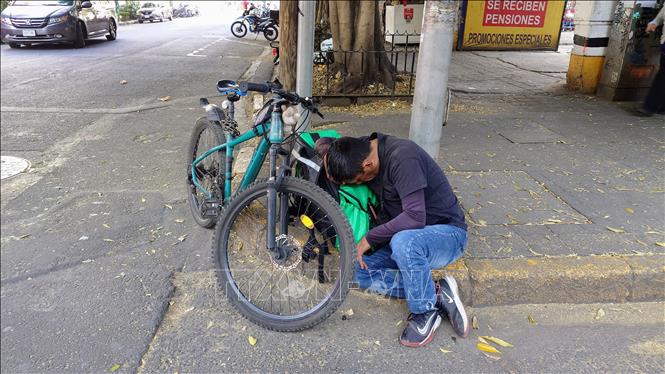 Một người đàn ông hành nghề shipper ngủ gục bên thùng hàng tại khu vực phố cổ thủ đô Mexico City, Mexico. Ảnh: Phi Hùng - PV TTXVN tại Mexico