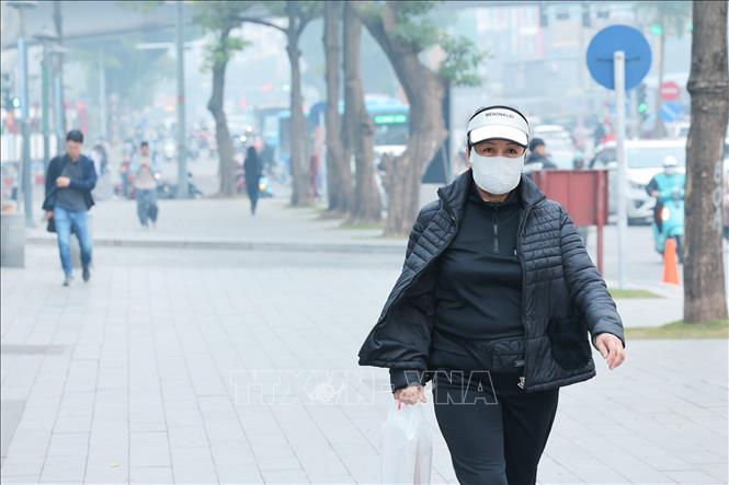 Người đi bộ bịt khẩu trang để hạn chế hít phải bụi mịn, không khí ô nhiễm. Ảnh: Lê Đông - TTXVN