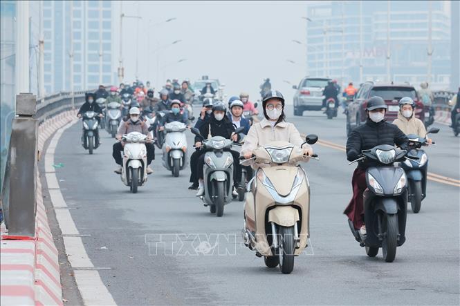 Người tham gia giao thông bịt khẩu trang để hạn chế hít phải bụi mịn, không khí ô nhiễm. Ảnh: Lê Đông - TTXVN