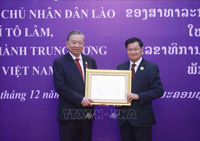 LPRP General Secretary and President of Laos Thongloun Sisoulith presents the Order to Party General Secretary To Lam. VNA Photo: Thống Nhất 