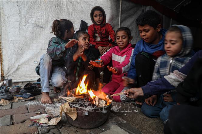 Người dân Palestine ngồi sưởi ấm tại nơi tránh trú tạm thời ở thành phố Gaza ngày 14/11/2025. Ảnh: THX/TTXVN