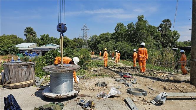 Công nhân Công ty Điện lực An Giang khẩn trương xây dựng trụ điện thuộc đường dây 110kV trên không từ trụ đấu nối cáp ngầm tiếp bờ hiện hữu đến vị trí điểm sự cố. Ảnh: TTXVN phát