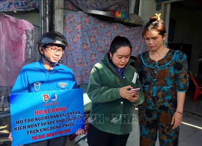 Đoàn viên đến tận khu dân cư hỗ trợ người dân cài đặt và kích hoạt sổ sức khỏe điện tử trên ứng dụng VNeID tại xã Phú Quới, tỉnh Vĩnh Long. Ảnh: Lê Thúy Hằng – TTXVN