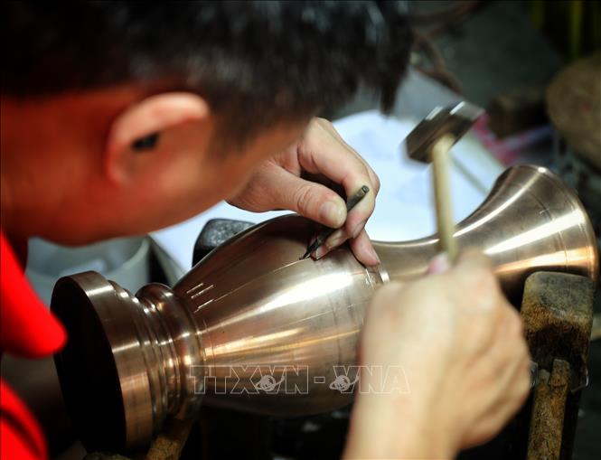 Nghề gò, đúc đồng đòi hỏi thao tác rất tỉ mỉ. Ảnh: Danh Lam-TTXVN