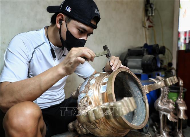 Nghề gò, đúc đồng đòi hỏi thao tác rất tỉ mỉ. Ảnh: Danh Lam-TTXVN