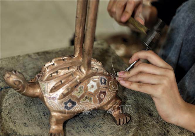 Nghề gò, đúc đồng đòi hỏi thao tác rất tỉ mỉ. Ảnh: Danh Lam-TTXVN