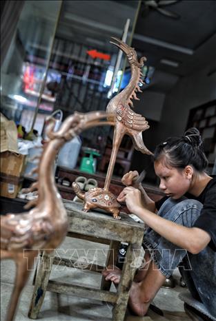 Nghề gò, đúc đồng đòi hỏi thao tác rất tỉ mỉ. Ảnh: Danh Lam-TTXVN
