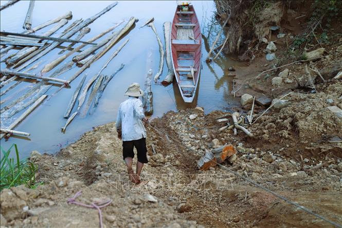 Kéo dây cáp tời xuống sông Nậm Nơn để cột vào thân gỗ trôi nổi trên mặt nước. Ảnh: Xuân Tiến - TTXVN 