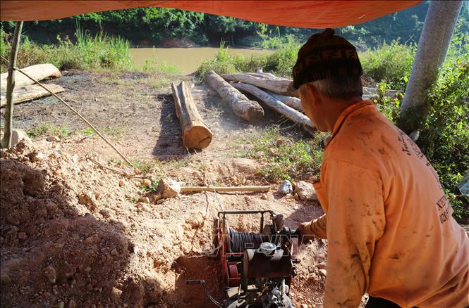 Người dân điều khiển máy tời để kéo một thân gỗ to, nặng, dài gần 4m từ bờ sông Nậm Nơn lên khu vực tập kết để cưa xẻ, sơ chế gỗ. Ảnh: Xuân Tiến - TTXVN 