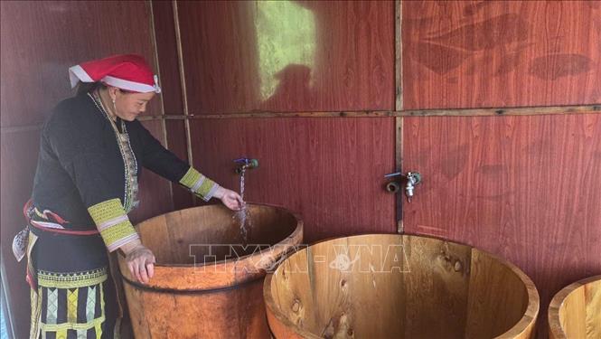 Preparing a Fokienia wooden tub for a herbal bath. Photo: Huong Thu – VNA