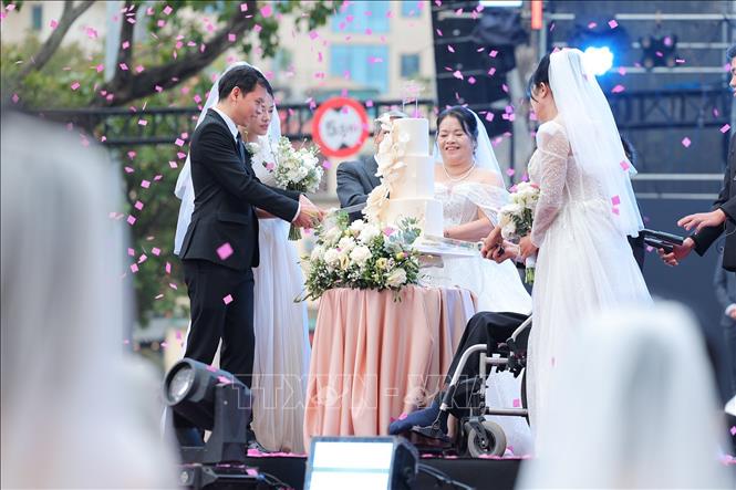 Đại diện 3 cặp đôi thực hiện nghi thức cắt bánh cưới. Ảnh: Lê Đông - TTXVN