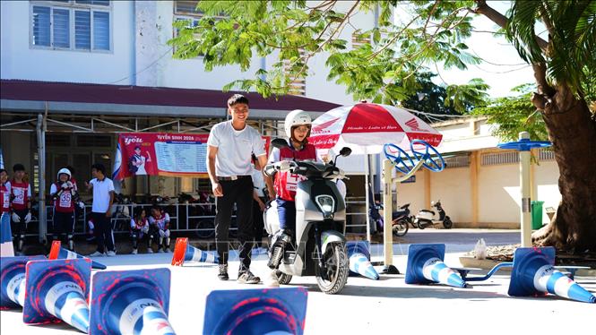 Cán bộ Trung tâm Lái xe an toàn (Công ty Honda Việt Nam) hướng dẫn học sinh kỹ năng điều khiển xe máy điện. Ảnh: Minh Phú – TTXVN