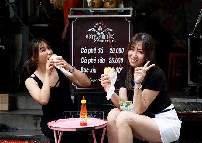 Khách du lịch Nhật Bản thưởng thức bánh mì ở quán cà phê vỉa hè đường Pasteur, phường Bến Thành, Thành phố Hồ Chí Minh. Ảnh: Hồng Đạt - TTXVN 
