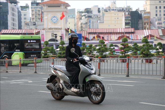 Người dân Thành phố Hồ Chí Minh đi xe máy phải bịt khẩu trang để ngăn ngừa bệnh hô hấp vì ô nhiễm không khí. Ảnh: Hồng Đạt - TTXVN 

