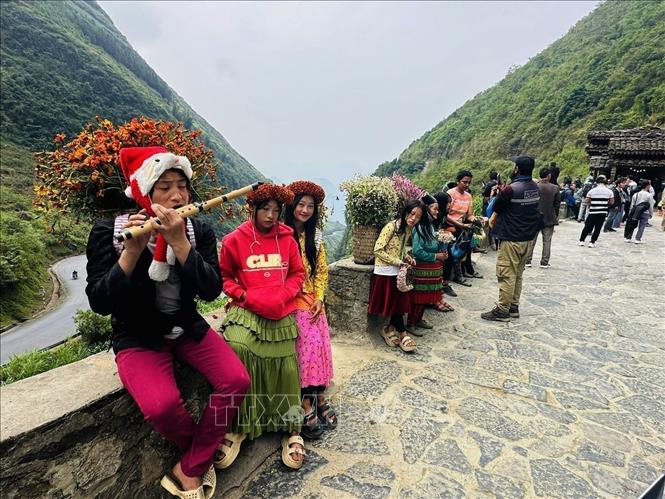 Mong children carrying baskets of flowers stand at the entrance to Lung Cam village, giving visitors a friendly and cheerful image. VNA Photo: Minh Tâm