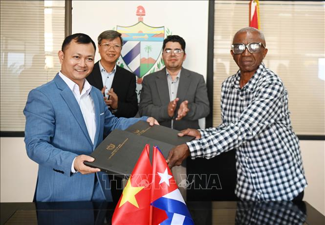 Ông Nguyễn Khắc Hoàng, Giám đốc công ty Hoàng Gia Việt, và đại diện của công ty nông nghiệp Alquizar, thuộc Tập đoàn doanh nghiệp Nông Lâm nghiệp Artemisa của Cuba, trao đổi văn bản ký kết. Ảnh: Việt Hùng-PVTTXVN tại Cuba