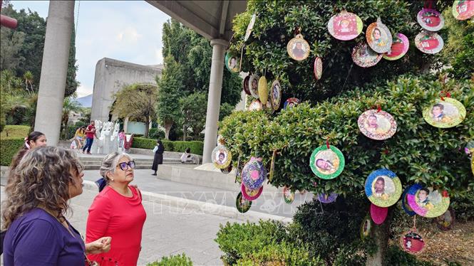 Người dân bên cây Noel được trang trí bằng ảnh của những người mất tích tại nhà thờ San Cristóbal, ngoại ô thủ đô Mexico City. Ảnh: Phi Hùng - PV TTXVN tại Mexico