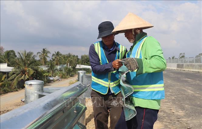 Công nhân thi công hạng mục an toàn giao thông trên cao tốc Cần Thơ - Cà Mau.Ảnh: Tuấn Phi - TTXVN