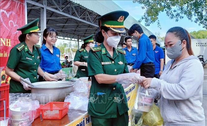 Cán bộ, chiến sĩ Đồn Biên phòng Vĩnh Nguơn (Ban chỉ huy Bộ đội Biên phòng tỉnh An Giang) trao những bát cháo nóng hổi, thơm phức đến tận tay người bệnh và người nhà bệnh nhân nghèo đang điều trị tại Bệnh viện Đa khoa Châu Đốc, tỉnh An Giang. Ảnh: Công Mạo-TTXVN