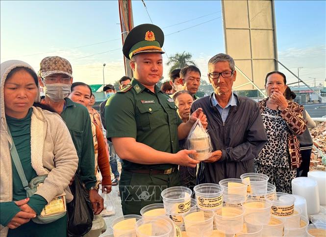 Cán bộ, chiến sĩ Đồn Biên phòng Vĩnh Nguơn (Ban chỉ huy Bộ đội Biên phòng tỉnh An Giang) trao những bát cháo nóng hổi, thơm phức đến tận tay người bệnh và người nhà bệnh nhân nghèo điều trị tại Bệnh viện Đa khoa Châu Đốc, tỉnh An Giang. Ảnh: Công Mạo-TTXVN