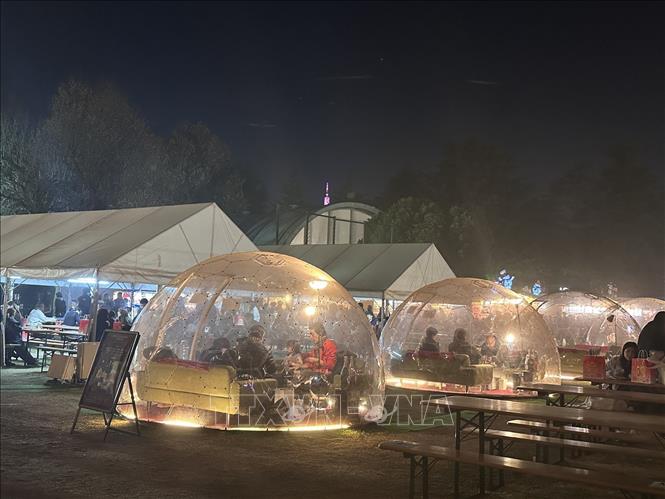 Từng nhóm người ngồi trong lều ấm áp để thưởng thức không khí Chợ Giáng Sinh Tokyo. Ảnh: Nguyễn Tuyến – PV TTXVN tại Nhật Bản