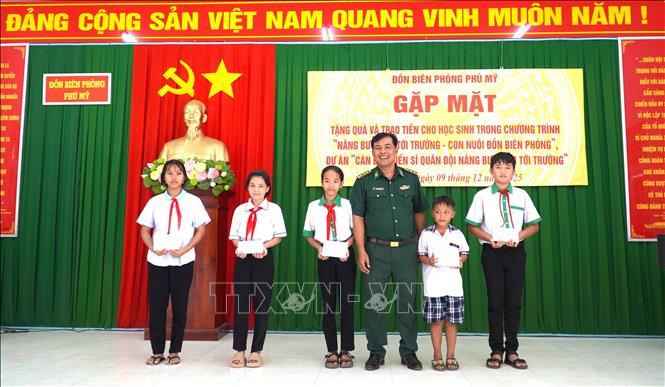 Thượng tá Danh Kim Huôl, Chính trị viên Đồn Biên phòng Phú Mỹ trao quà cho các học sinh thuộc chương trình “Nâng bước em tới trường - Con nuôi Đồn Biên phòng”. Ảnh: Văn Sĩ - TTXVN