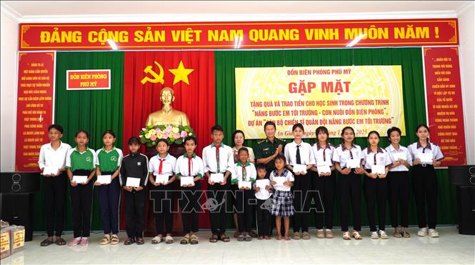 Trung tá Bùi Thanh Ngàn, Đồn trưởng Đồn Biên phòng Phú Mỹ trao quà cho các học sinh thuộc dự án “Cán bộ chiến sĩ Quân đội nâng bước em đến trường”. Ảnh: Văn Sĩ - TTXVN