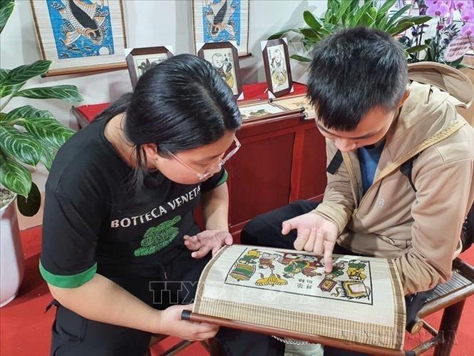 Người dân xem và trải nghiệm ở gian trưng bày tranh dân gian Đông Hồ - Mộc bản (Bắc Ninh) tại Trung tâm Hội chợ Triển lãm quốc gia (Đông Anh, Hà Nội). Ảnh: Nguyễn Trọng Lịch- TTXVN