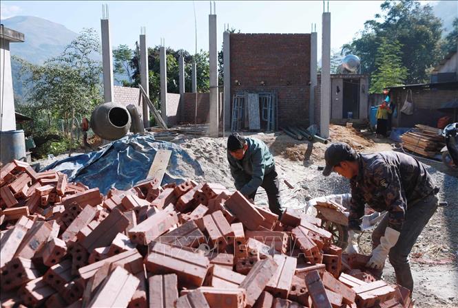 Người dân ở bản Nà Cùng, xã Phong Thổ, cùng nhau hỗ trợ giúp ngày công để xây dựng những ngôi nhà mới thay cho những ngôi nhà tạm, nhà dột nát. Ảnh: Việt Dũng - TTXVN 