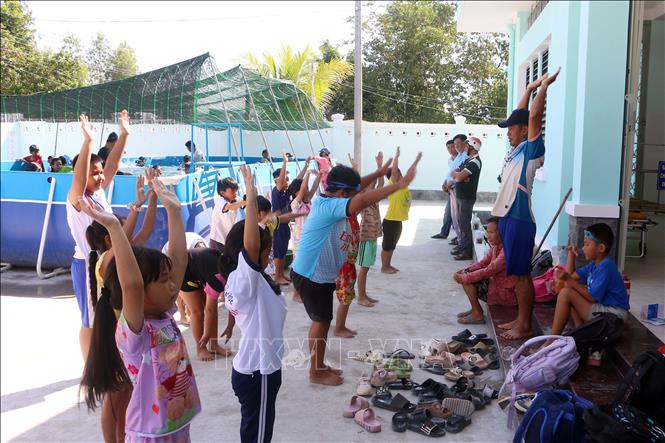 Khởi động trước khi tham gia lớp học bơi. Ảnh: Trung Kiên - TTXVN