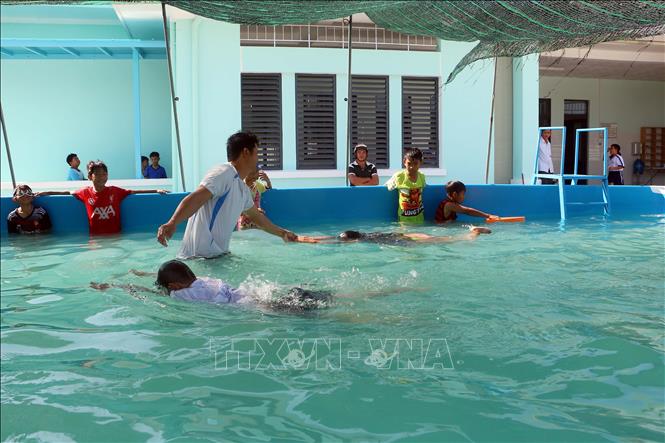 Giáo viên hướng dẫn kỹ năng bơi lội cho học sinh tham gia lớp học. Ảnh: Trung Kiên - TTXVN