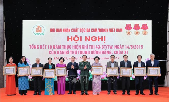 Trung tướng Nguyễn Hữu Chính, Chủ tịch Hội Nạn nhân chất độc da cam/dioxin Việt Nam và Ông Vi Tư Liệu, Vụ trưởng Vụ Đoàn thể nhân dân, Ban Tuyên giáo và Dân vận Trung ương trao bằng khen của Ban Tuyên giáo và Dân vận Trung ương cho các tập thể có đóng góp tích cực trong việc hỗ trợ nạn nhân chất độc da cam/dioxin Việt Nam. Ảnh: Lê Đông - TTXVN