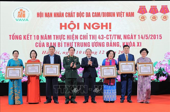 Trung tướng Nguyễn Hữu Chính, Chủ tịch Hội Nạn nhân chất độc da cam/dioxin Việt Nam và Ông Vi Tư Liệu, Vụ trưởng Vụ Đoàn thể nhân dân, Ban Tuyên giáo và Dân vận Trung ương trao bằng khen của Ban Tuyên giáo và Dân vận Trung ương cho các cá nhân có đóng góp tích cực hỗ trợ nạn nhân chất độc da cam/dioxin Việt Nam. Ảnh: Lê Đông - TTXVN