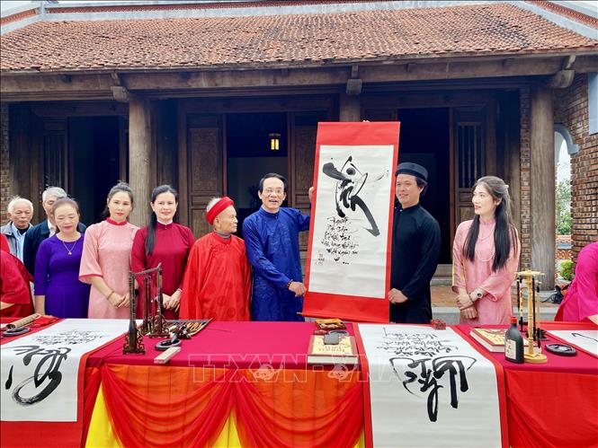 Các nghệ nhân trao bức thư pháp Truyện Kiều cho đại diện Ban tổ chức. Ảnh: Hữu Quyết - TTXVN