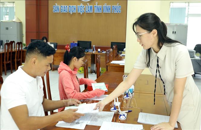 Nhân viên Trung tâm dịch vụ việc làm tỉnh Phú Thọ hướng dẫn người lao động viết thông tin đăng ký tìm việc làm. Ảnh: Hoàng Hùng - TTXVN